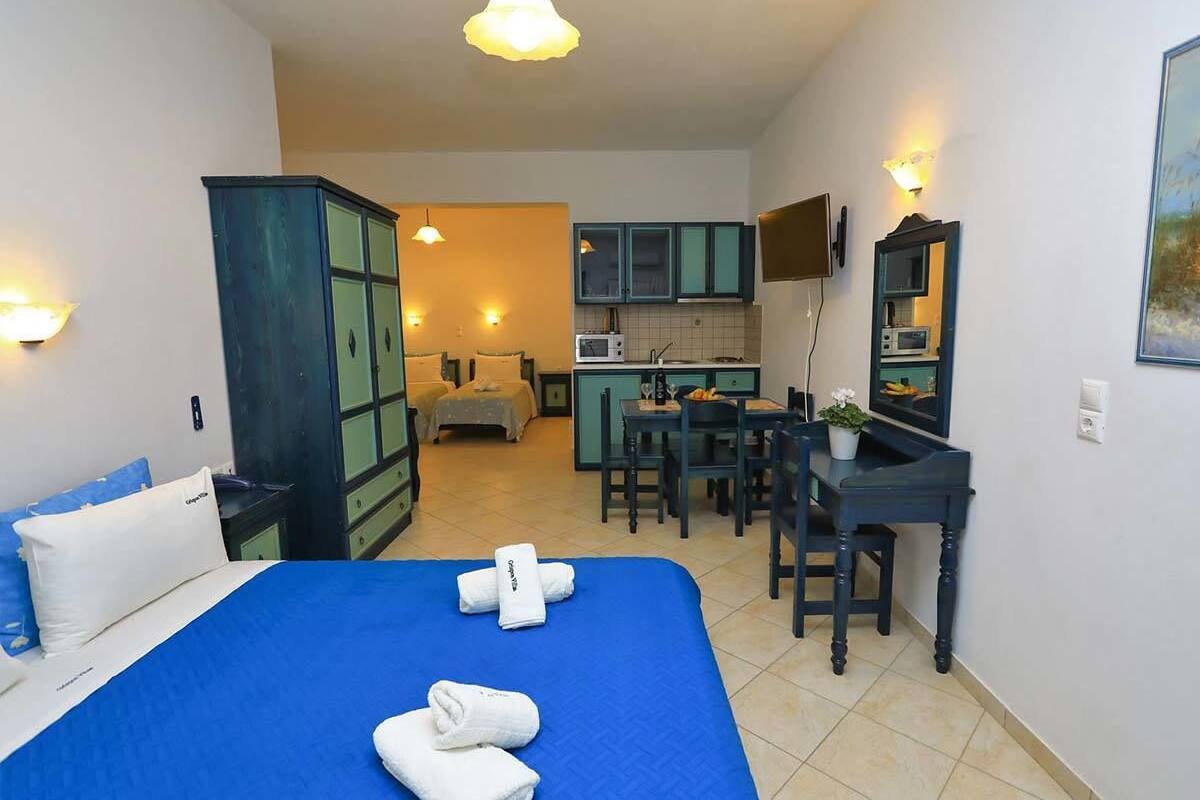 Een hotelkamer met een bed, bureau, kitchenette en badkamer.
