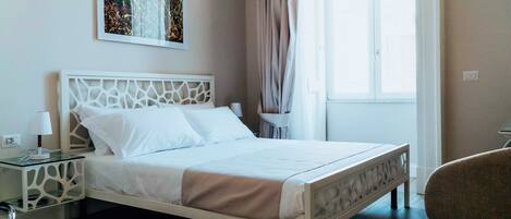 A neatly made bed with white linens, a modern headboard, and a bedside table with a lamp.