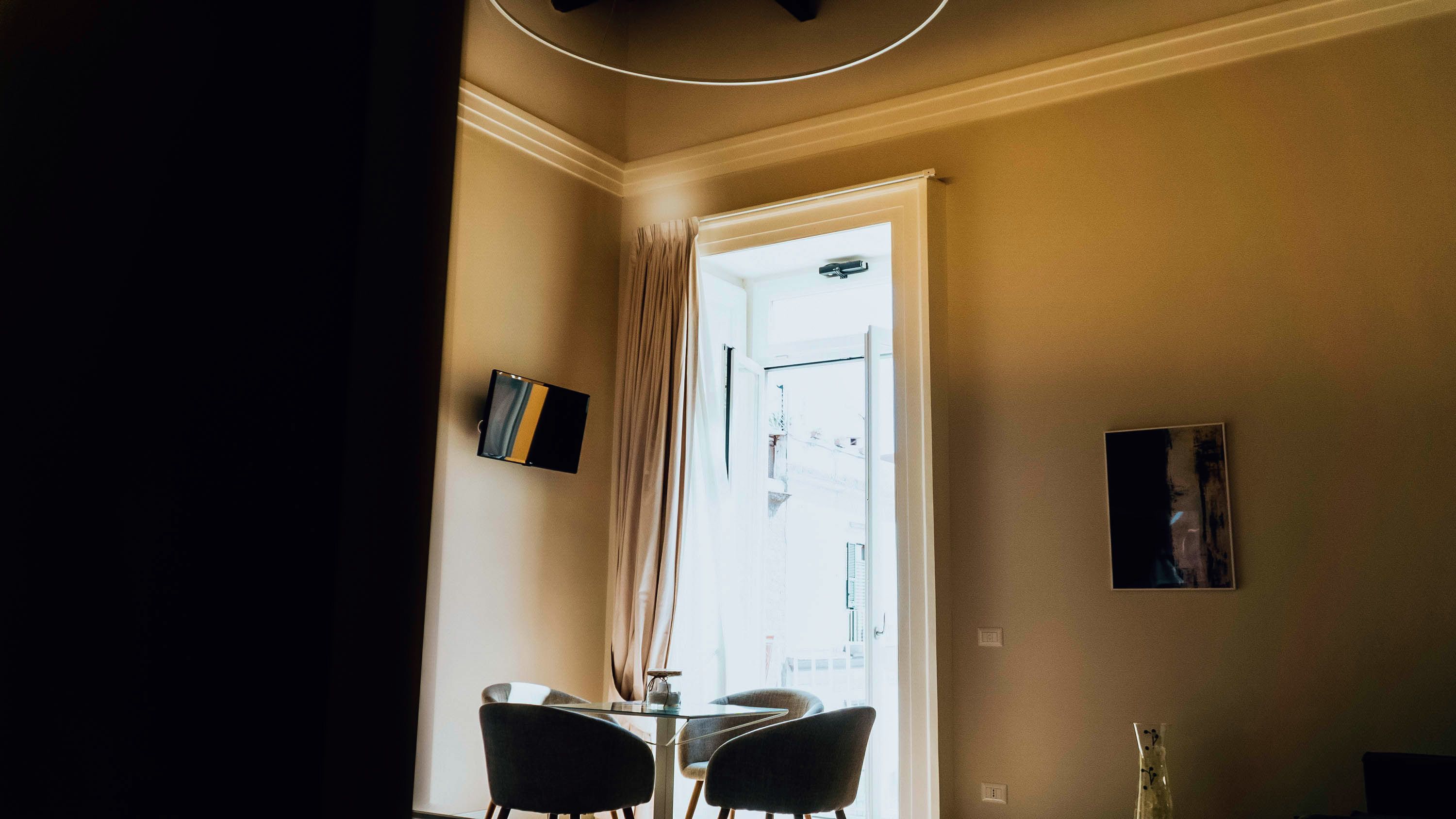 A room with a dining table and chairs, a window with curtains, and a door leading outside.