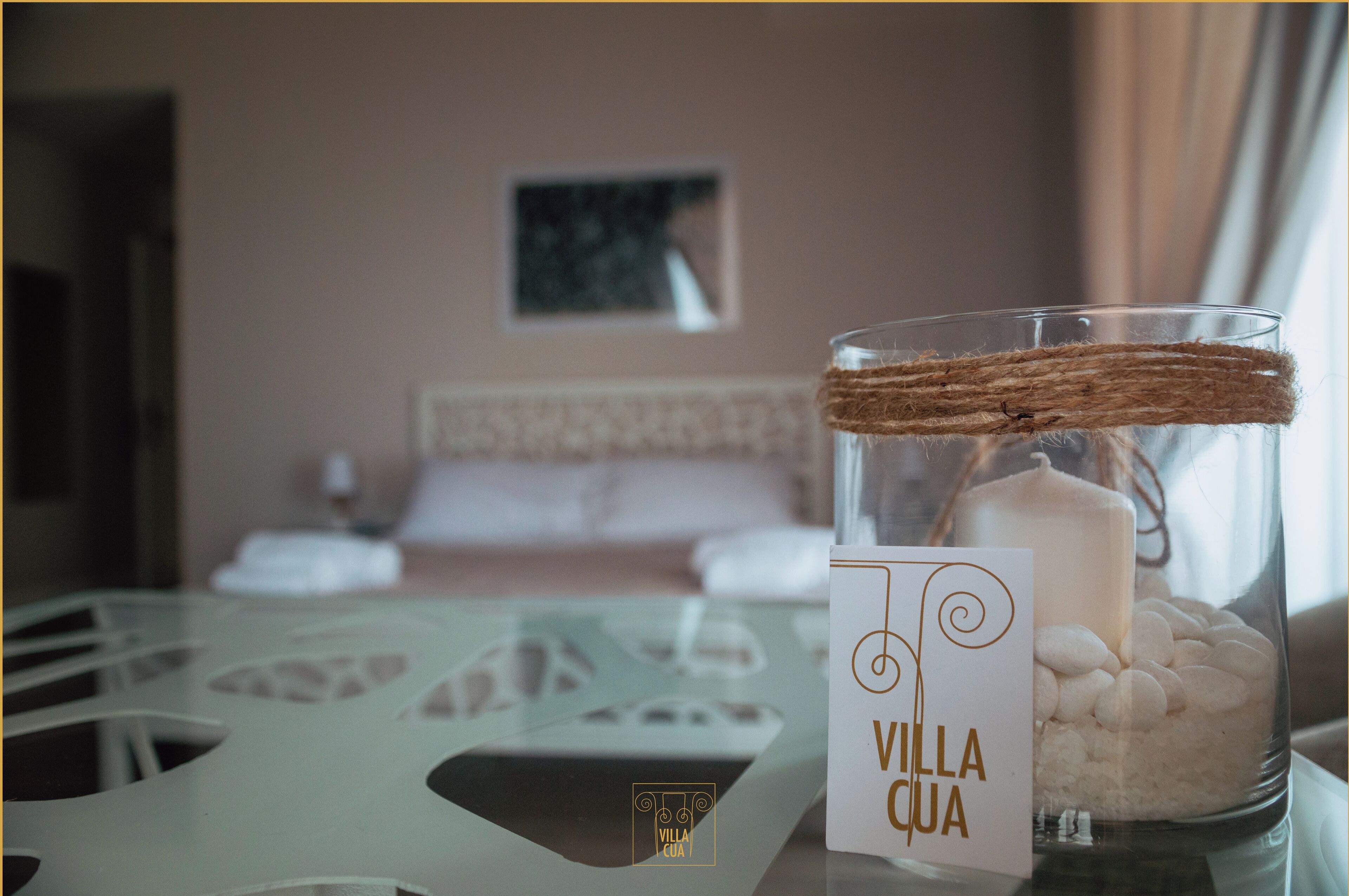 Una habitación con una cama, un candelabro de vidrio con una etiqueta y un cuadro en la pared.