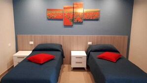 A twin room with two beds, each with a red pillow, and a wall-mounted painting above. - HOLIDAY HOUSE MANFREDI HOME (Polignano a Mare)