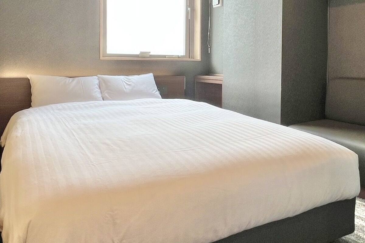 Un dormitorio moderno con una cama grande, una ventana y un banco empotrado.
