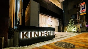 Entrada de un hotel con un cartel que dice "KINHOTEL" y una señal de flecha direccional arriba.