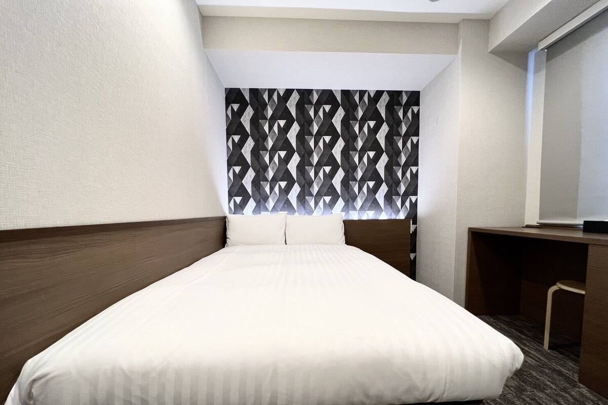 Una habitación de hotel con cama, escritorio y cabecera estampada.