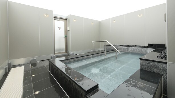 Un área de piscina interior moderna con suelo de vidrio, barandillas metálicas y un diseño minimalista.
