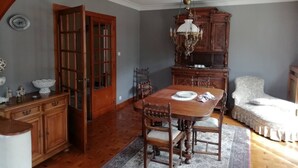 Zona pranzo con tavolo e sedie in legno, un lampadario e un ampio armadio in legno.