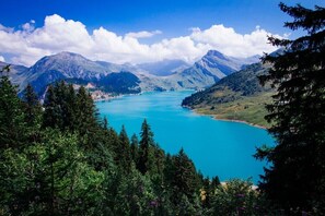 A mountainous landscape with a turquoise lake surrounded by dense forests and snow-capped peaks.