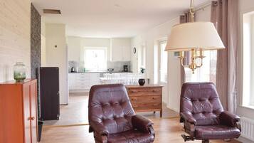 Un salon spacieux avec deux fauteuils en cuir, une table basse en bois et une grande fenêtre agrémentée de rideaux.