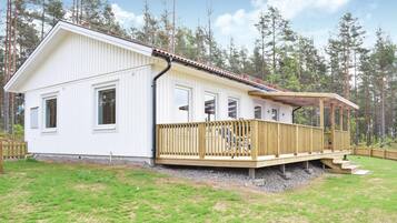 Une maison blanche à deux étages, dotée d’une terrasse en bois et d’un porche abrité.
