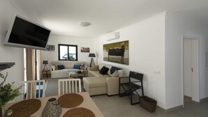 A modern living room with a flat-screen TV, a sofa set, a coffee table, and a dining area with a table and chairs. - Exclusive T2 apartment in the center of Cabanas de Tavira (Cabanas de Tavira)