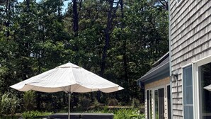 Um terraço com mobiliário para área externa, uma banheira de hidromassagem e um grande guarda-sol.