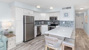 A modern kitchen with white cabinetry, stainless steel appliances, a large island, and a tiled backsplash. - Bayside Villa 4208 | Stunning Harbourview Residence| Walk to the Beach (Captiva)