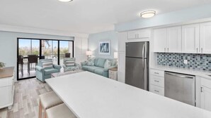 A modern kitchen with white cabinets, a stainless steel refrigerator, and a large island. - Bayside Villa 4208 | Stunning Harbourview Residence| Walk to the Beach (Captiva)