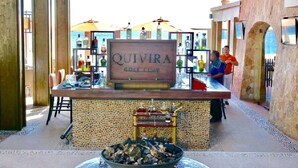 Eine Bar mit einer Beschilderung, auf der "QUIVIRA GOLD CLUB" steht, und einer Auswahl an Spirituosenflaschen.