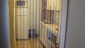A room with a kitchen area visible through a curtain. - Lava Apartment (Vestmannaeyjar)