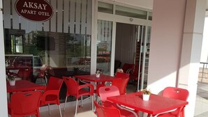 Un espace extérieur aménagé avec des chaises et des tables rouges, situé à l’hôtel Aksay Apart.