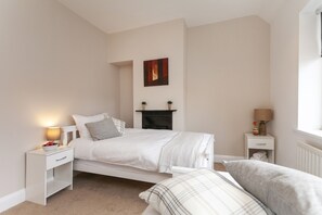 A bedroom with a bed, bedside tables, a fireplace, and a window. - Astley 3 bedroom house (Leicester)