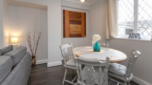 Een eetruimte met een ronde tafel, witte stoelen en een vaas met bloemen.