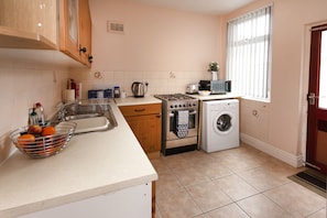 Compact kitchen with stainless steel sink, gas stove, microwave, and oven.