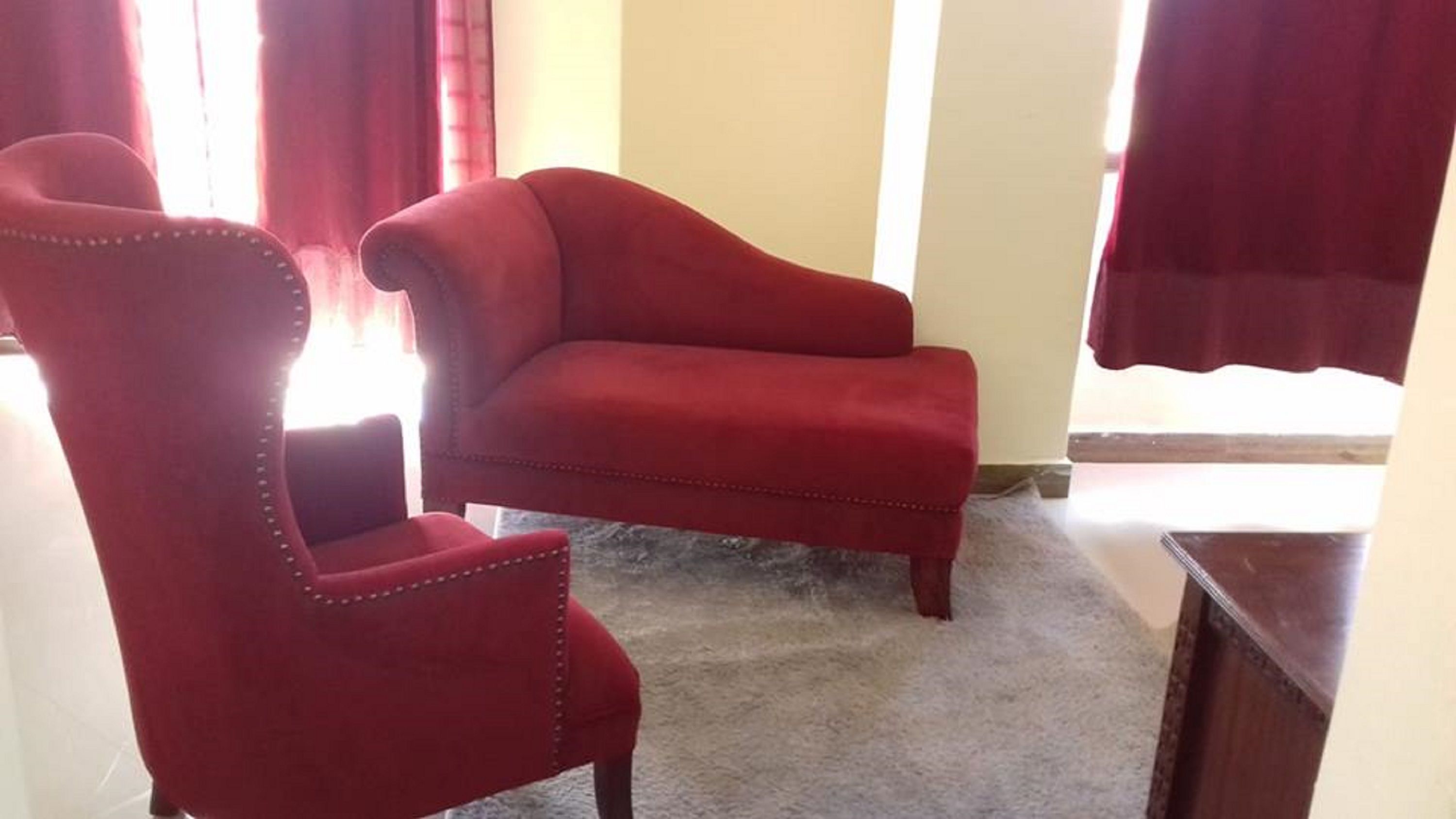 Een kamer met een rode fauteuil en een bijpassende bank.