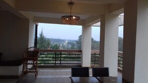 Un balcon donnant sur un paysage rural, une chaise en bois et une table.
