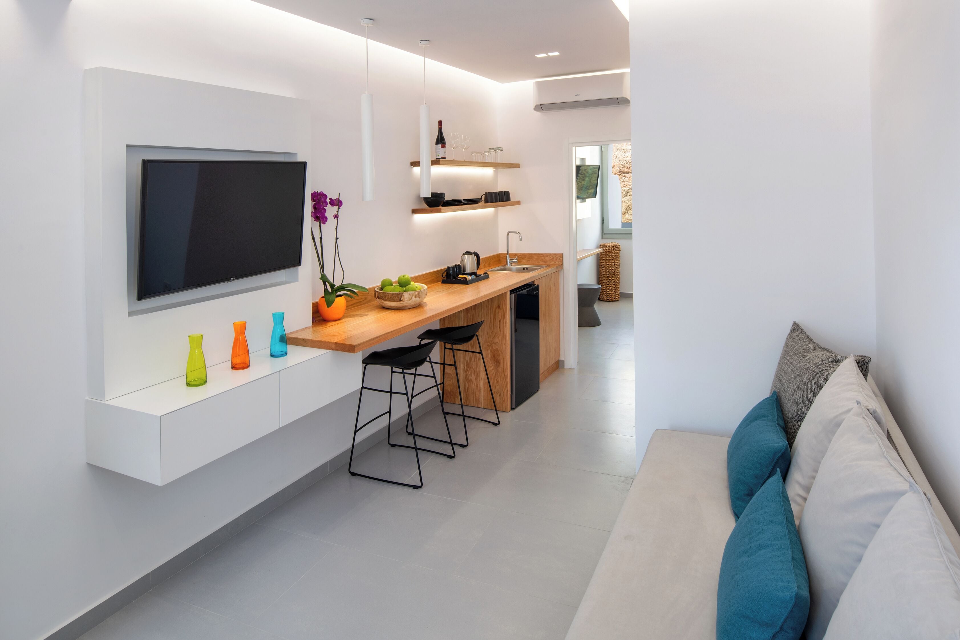 Eine moderne Küche mit Flachbildfernseher, Barhocker und einem Essbereich.