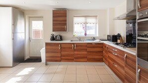 Eine moderne Küche mit Holzschränken, Edelstahlgeräten und einem großen Fenster.