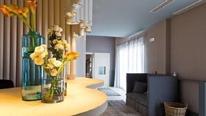A modern reception area with a curved counter, vases of flowers, and a seating area with a sofa and a basket. - Masseria Sant'Eleuterio (Collepasso)