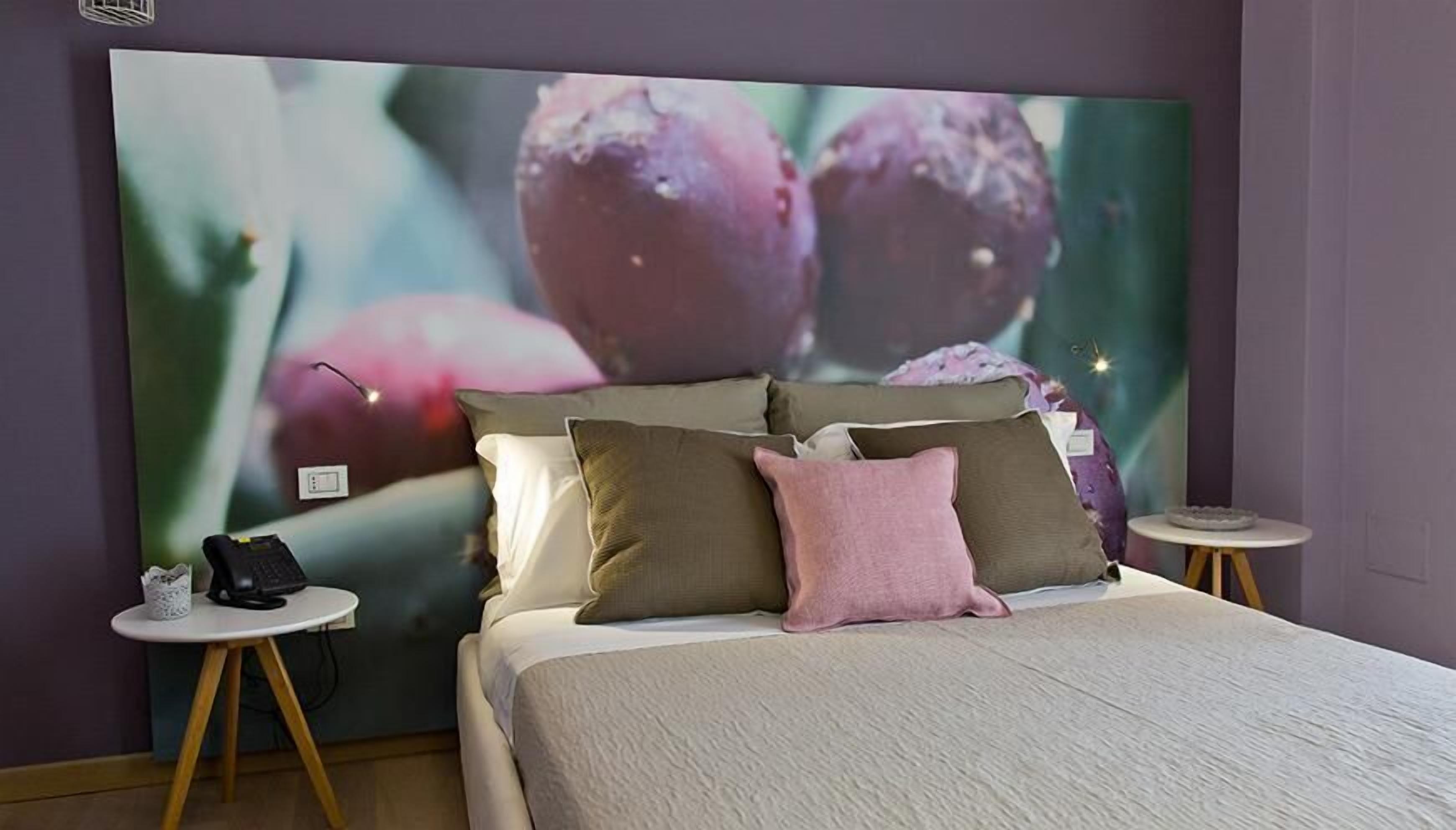 Un dormitorio con una cama grande, dos mesitas de noche y un televisor empotrado mostrando fruta.