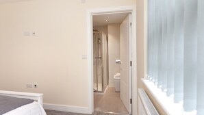 A bedroom with a bed, a shower, and a bathroom. - Condron 3 bedroom house (Worksop)