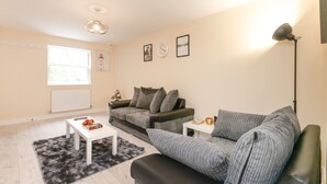 A modern living room with a sofa, a coffee table, and a lamp. - Condron 3 bedroom house (Worksop)