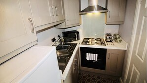 A compact kitchen with white cabinets, a gas stove, a microwave, and a sink.