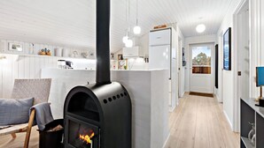 Una cucina moderna con stufa a legna, mobili bianchi e vista all'esterno.