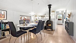 Una cucina moderna con isola centrale, camino a legna integrato e zona pranzo con tavolo rotondo e sedie.