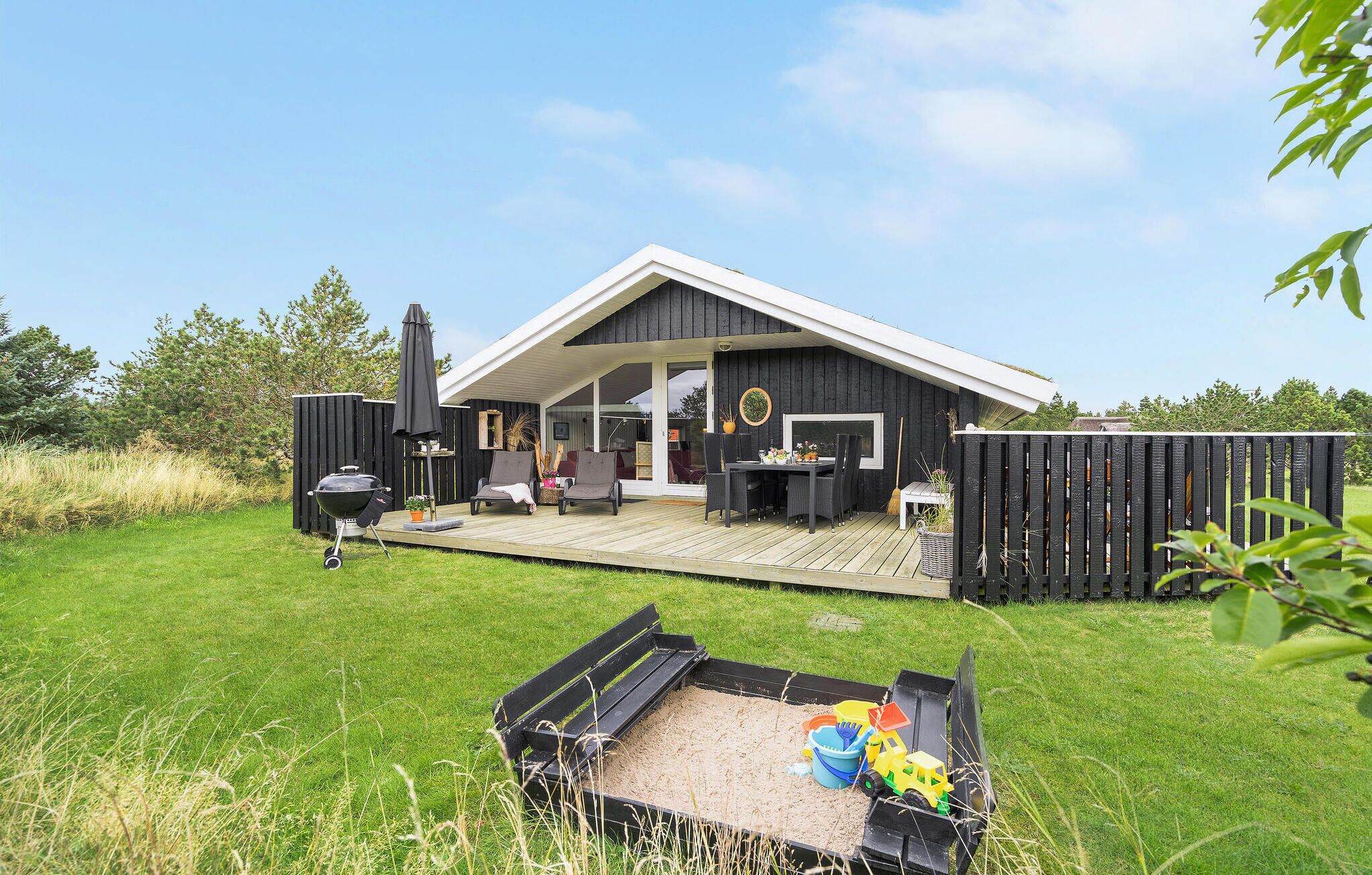 A modern house with a deck, outdoor furniture, and a barbecue grill.
