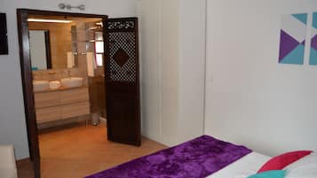 Un dormitorio con una cama, un edredón púrpura y una almohada blanca.