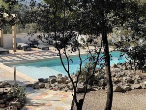 Un área de piscina con sillas de descanso y un deck con baldosas de piedra.