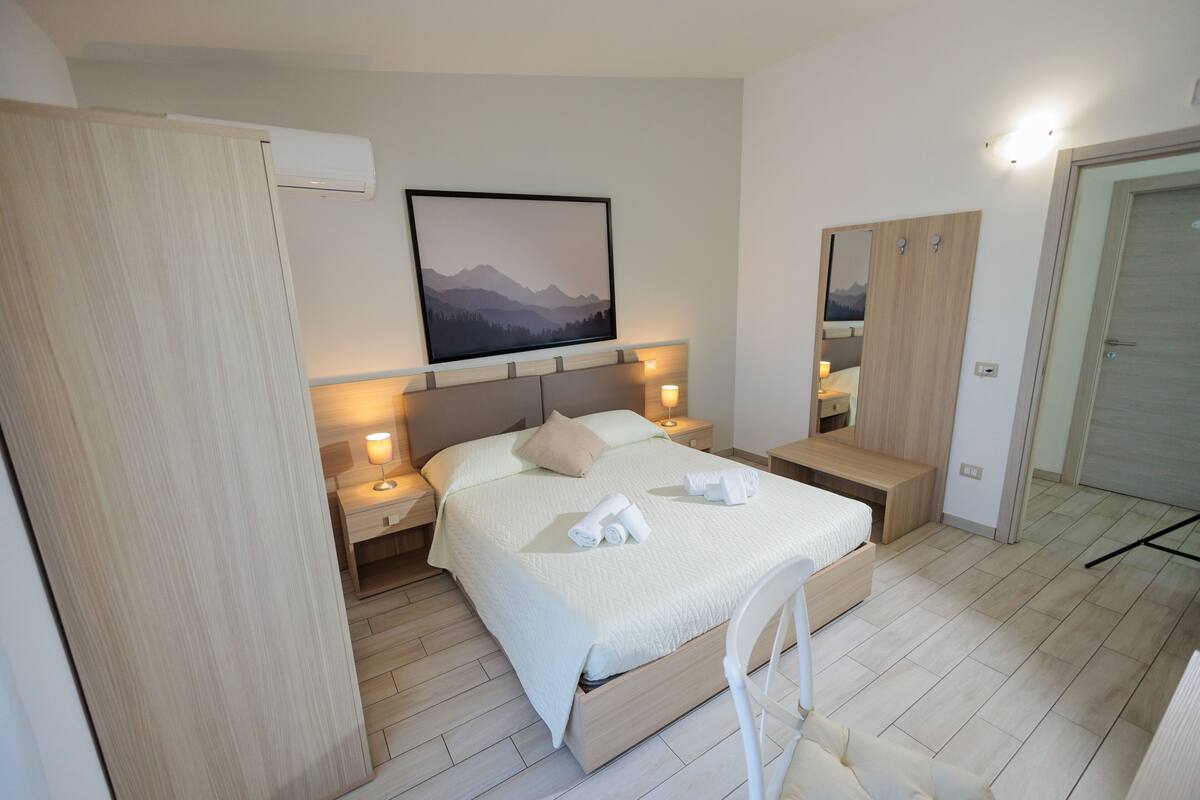 A modern bedroom with a bed, bedside tables, a wardrobe, and a mounted picture.