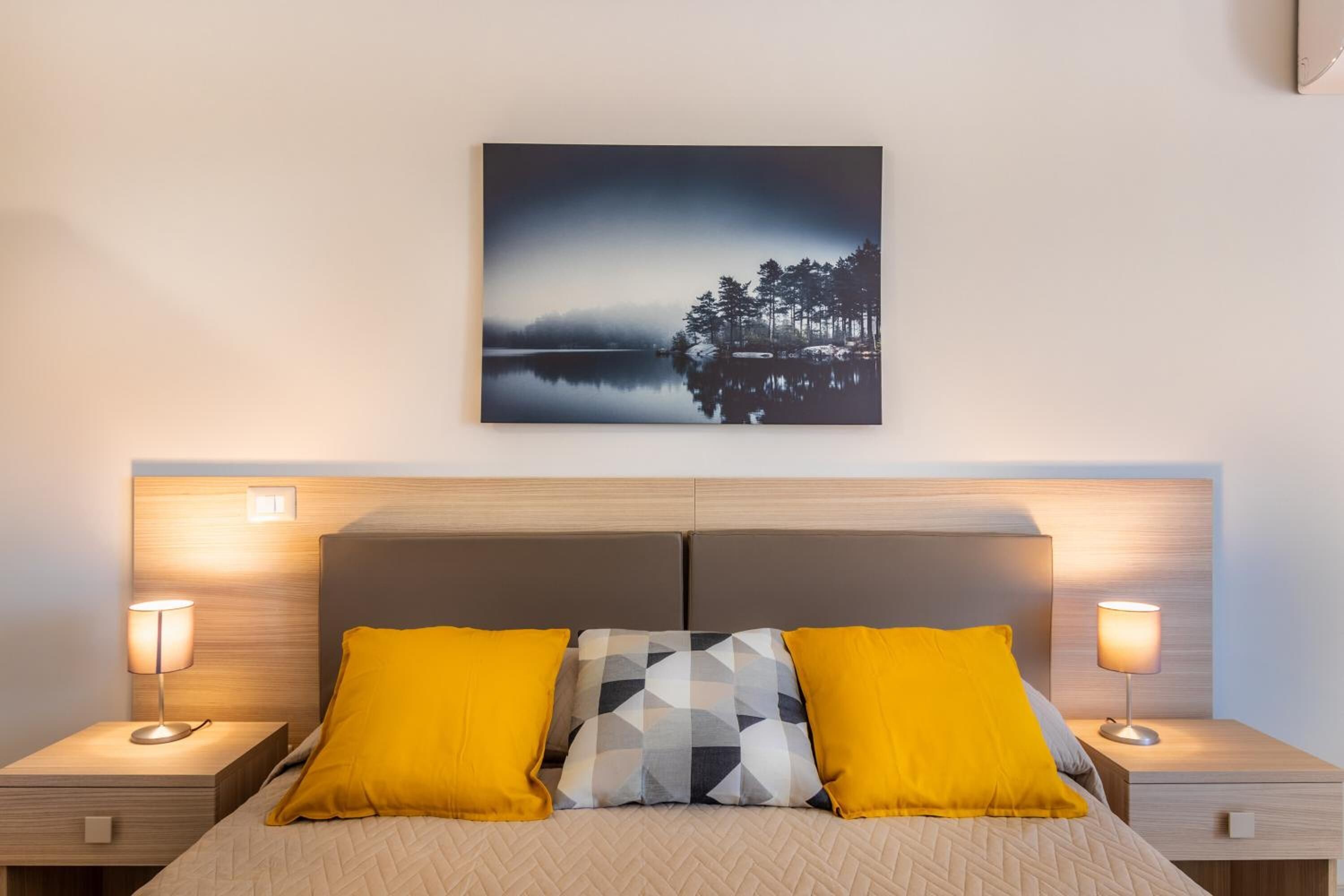 Une chambre à coucher avec un lit, deux tables de chevet et un tableau accroché au mur.