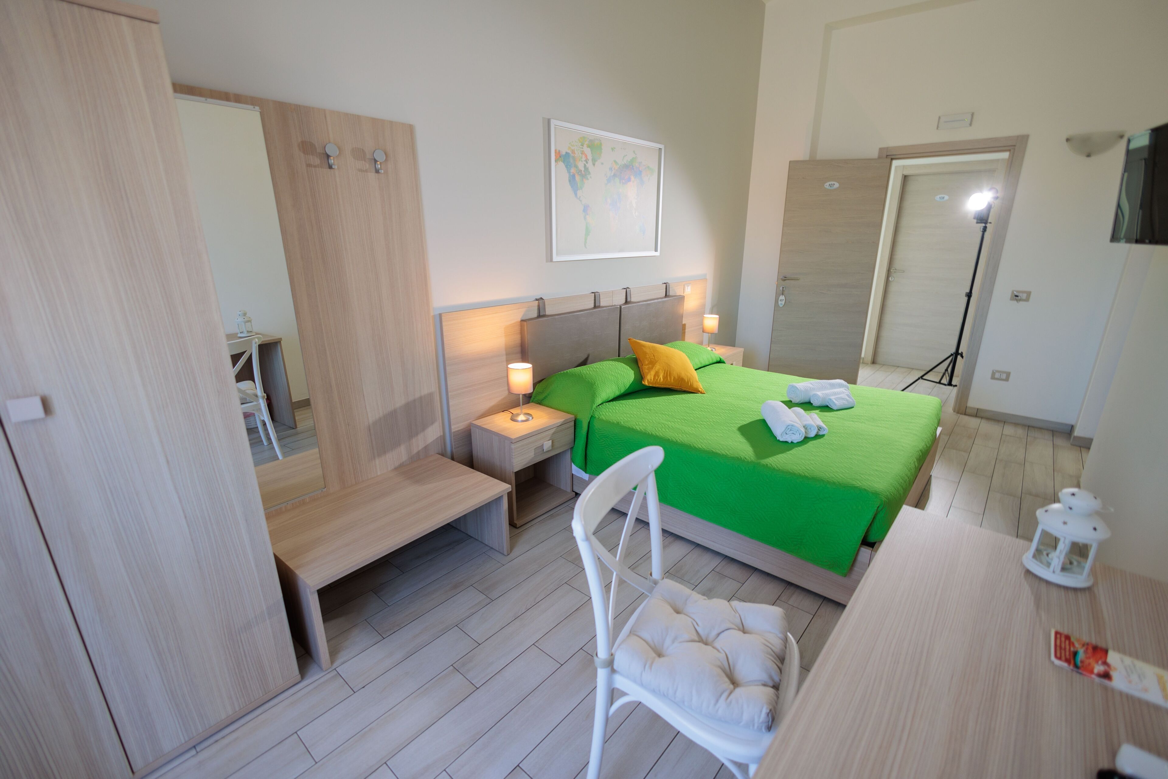 A hotel room with a bed, bedside table, chair, and a desk.