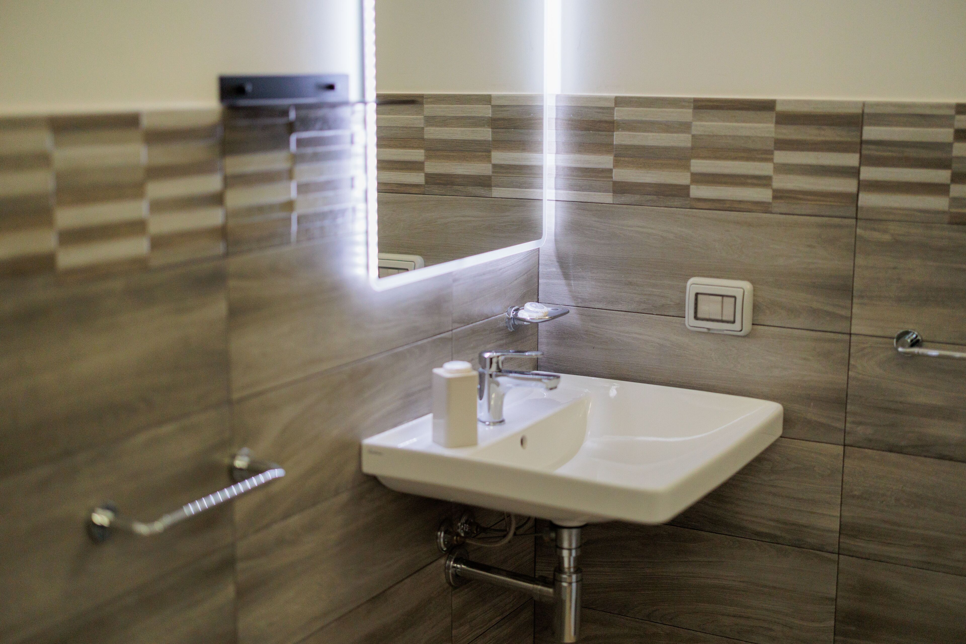 A modern bathroom with a rectangular sink, a mirror, and a towel rack.