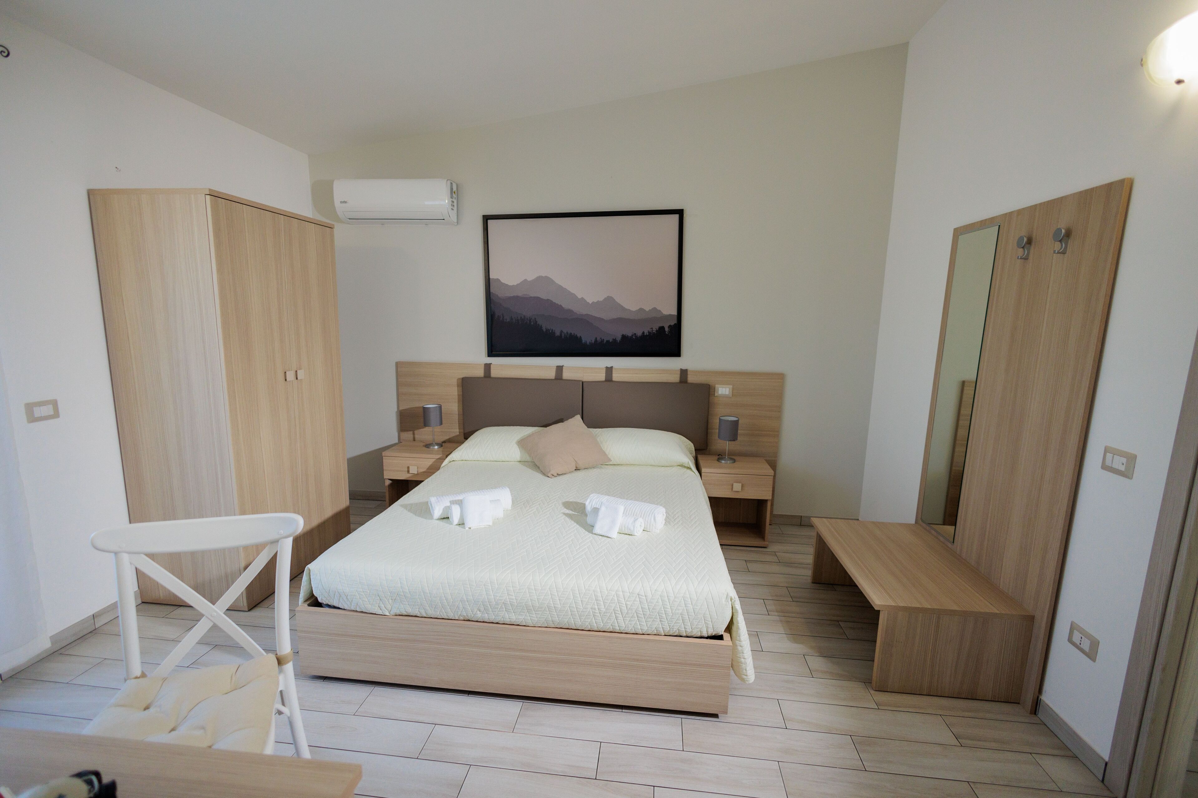 Una camera da letto moderna con un letto, comodini, una panca e un armadio.