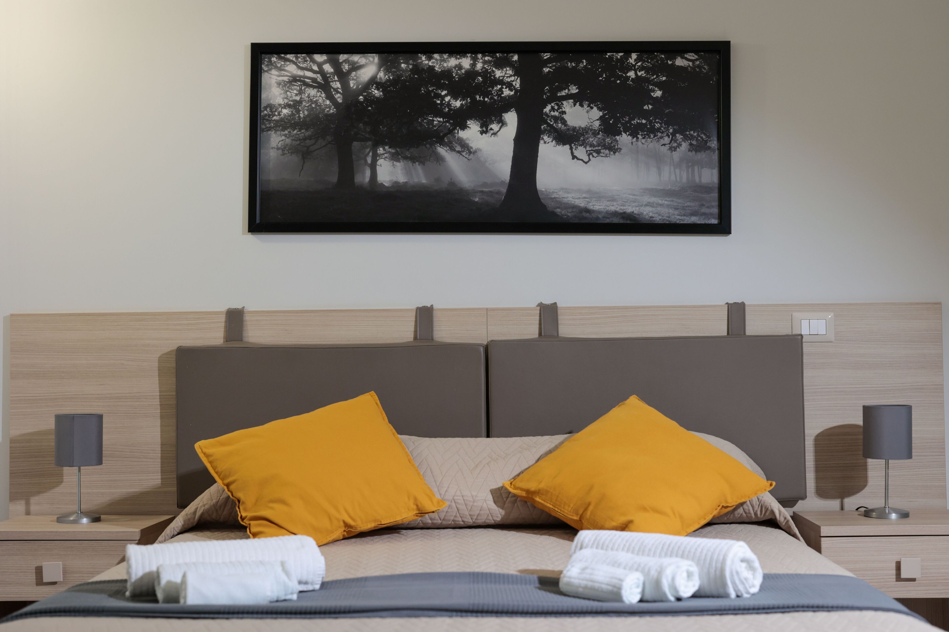 Un letto rifatto con due cuscini, una testiera e un comodino con una lampada.