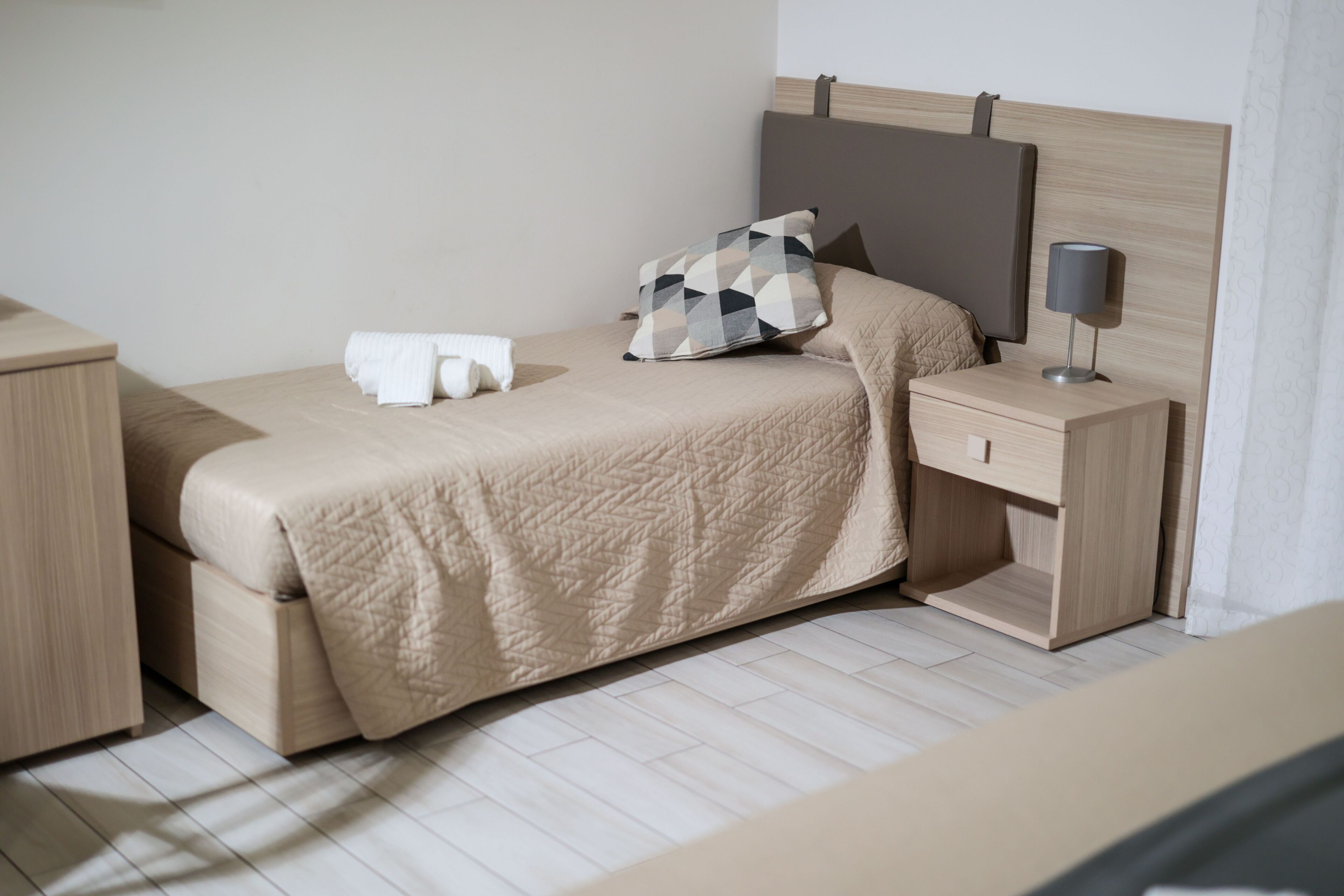 A neatly arranged bedroom with a bed, bedside table, and a lamp.
