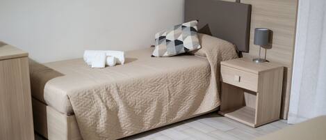 A neatly arranged bedroom with a bed, bedside table, and a lamp.