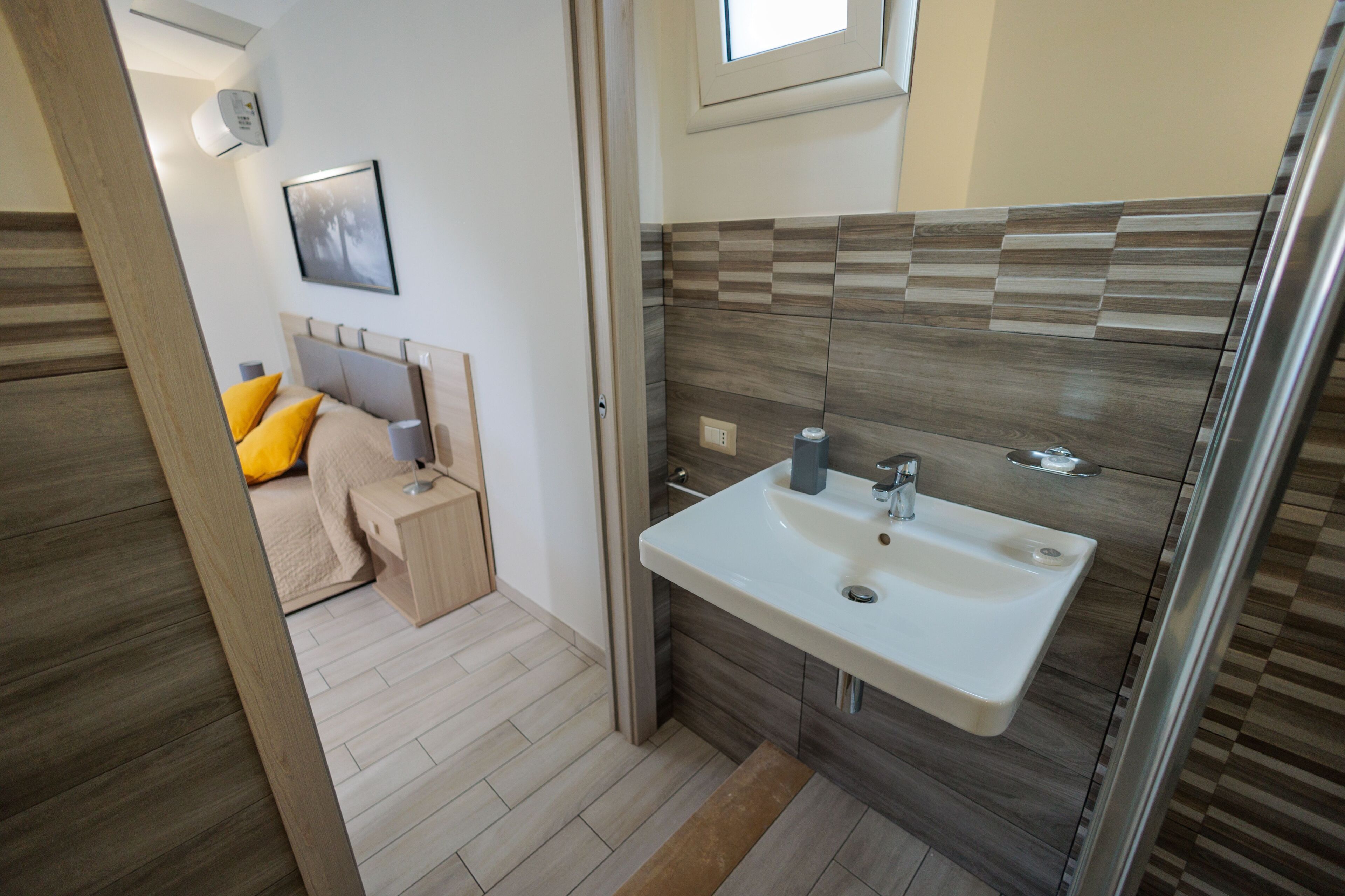 A compact bathroom with a sink, mirror, and a shower area.