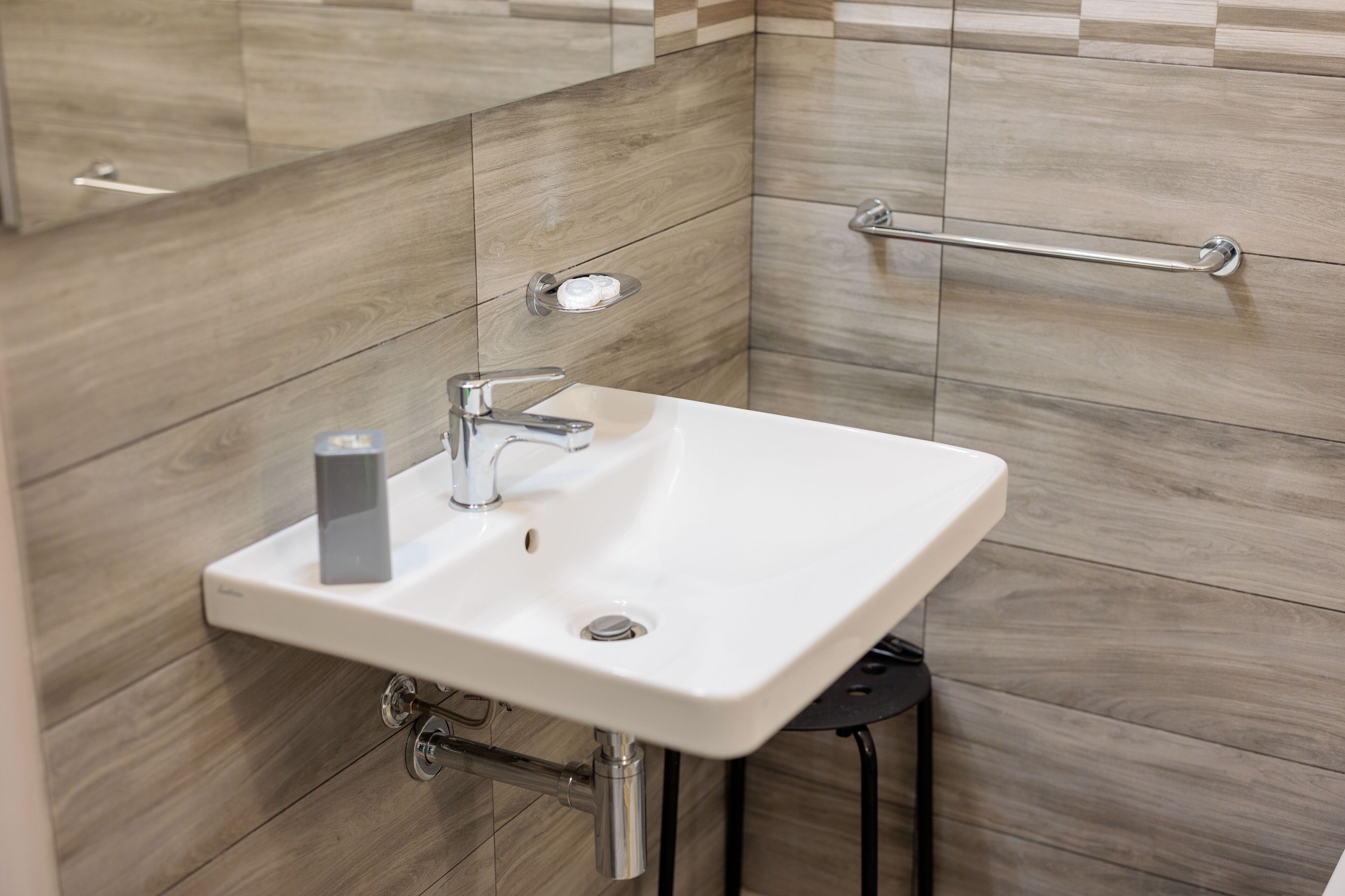 A bathroom with a white sink, chrome faucet, and a towel rack.