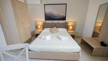 Een moderne slaapkamer met een groot bed, bedlampjes, een hoofdbord, een kledingkast, een bankje en een ingelijste foto aan de muur.