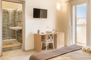 Une chambre moderne comprenant un lit, un bureau, une chaise, un téléviseur et un espace douche.