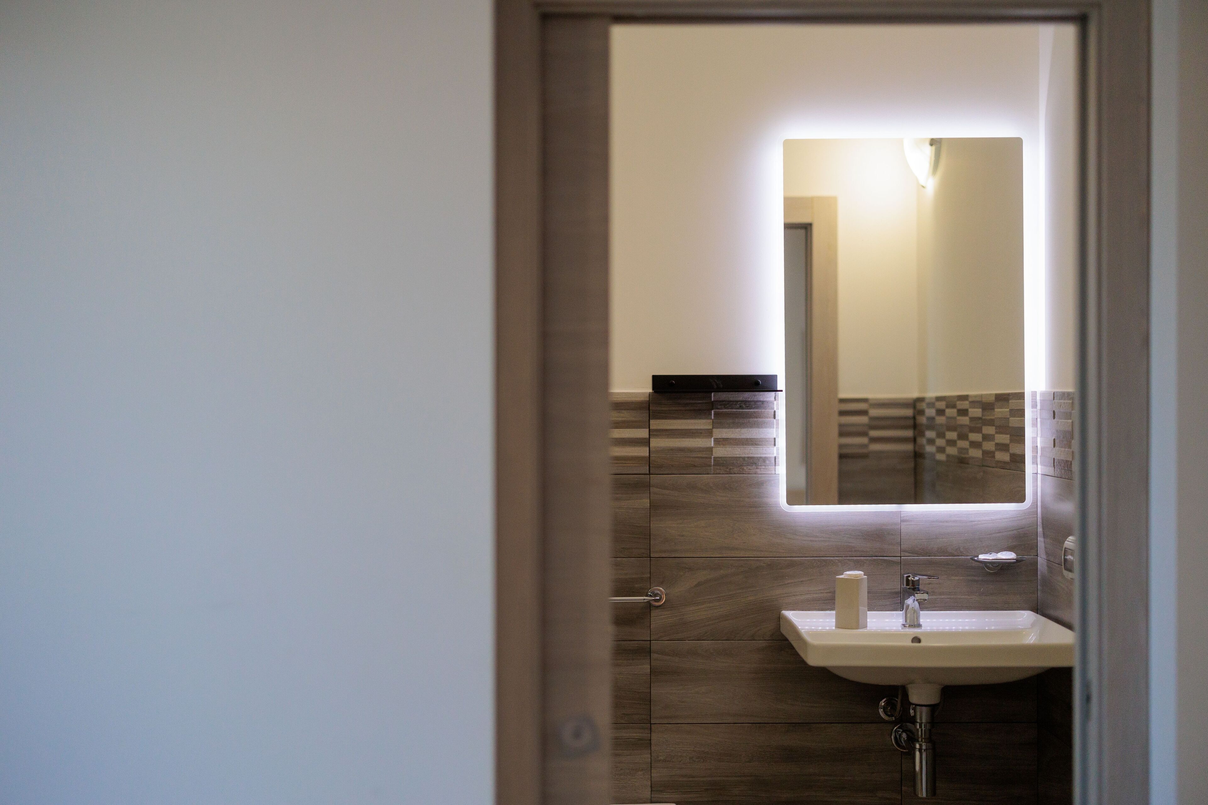 A bathroom with a sink, mirror, and tiled walls.